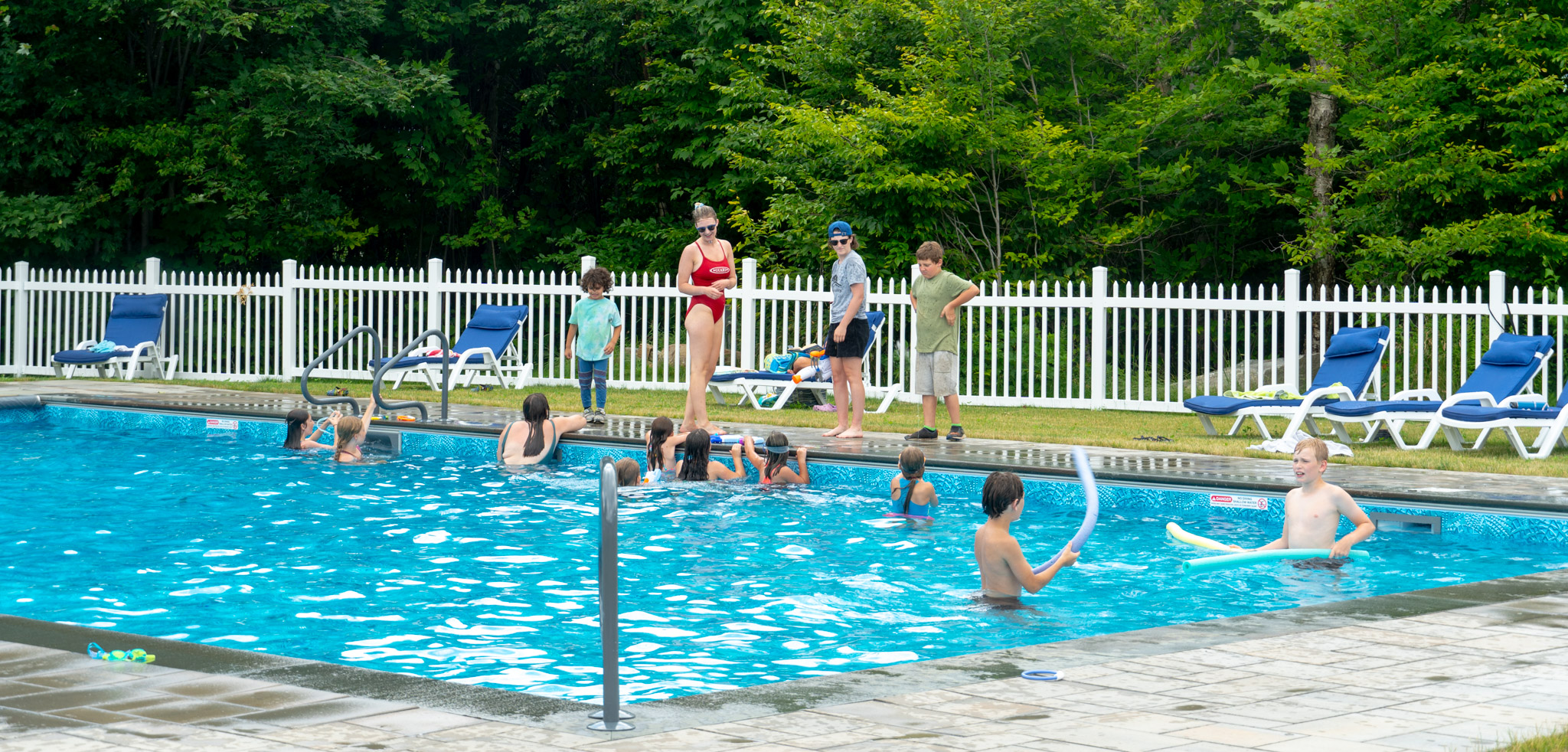 children enjoy a pool while a lifeguard watches